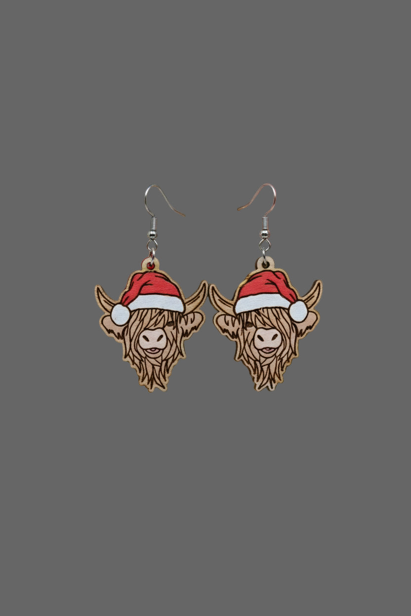 Wooden Highland cow earrings with Santa hats on a Hylidae Boutique card.