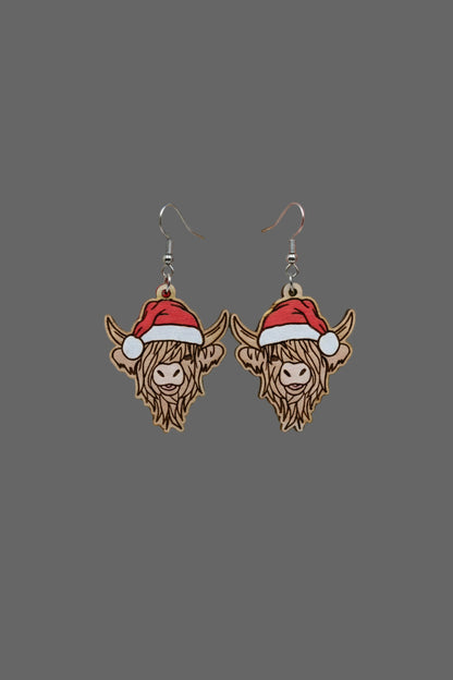Wooden Highland cow earrings with Santa hats on a Hylidae Boutique card.